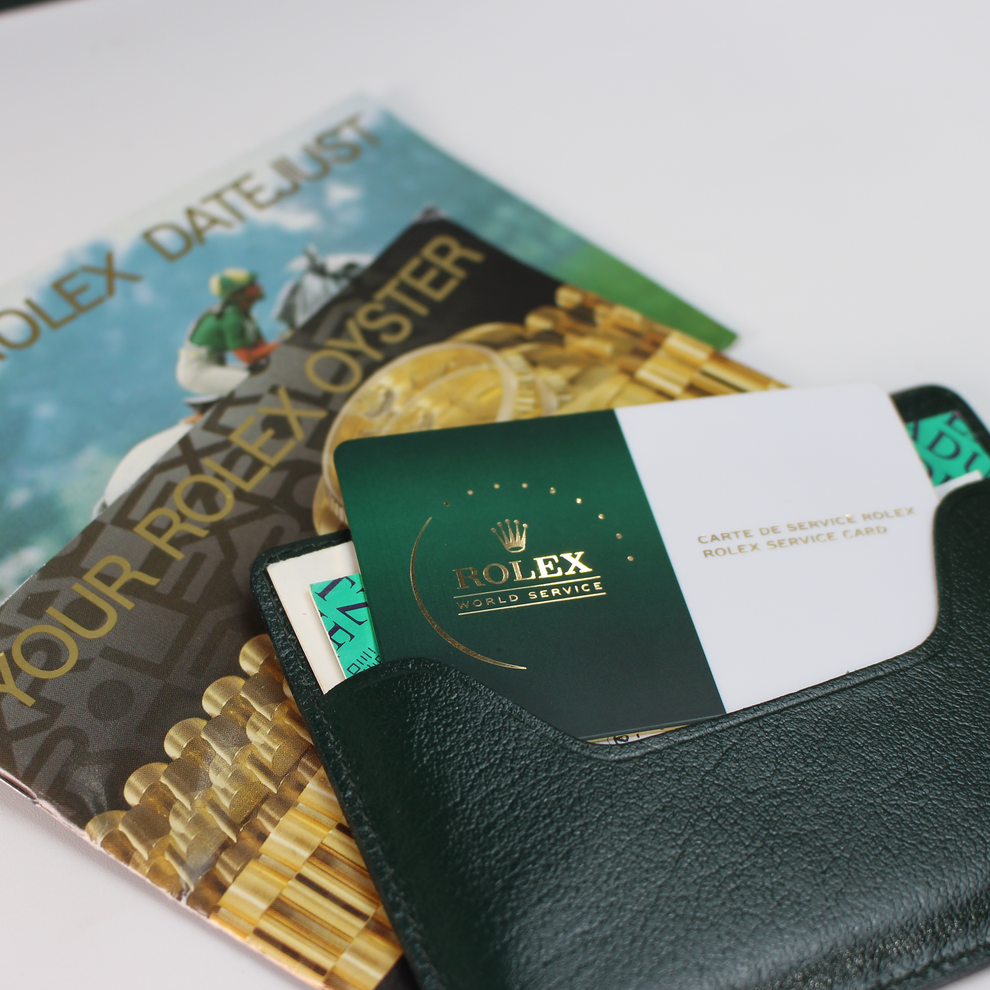 Rolex service card and promotional materials on a white surface