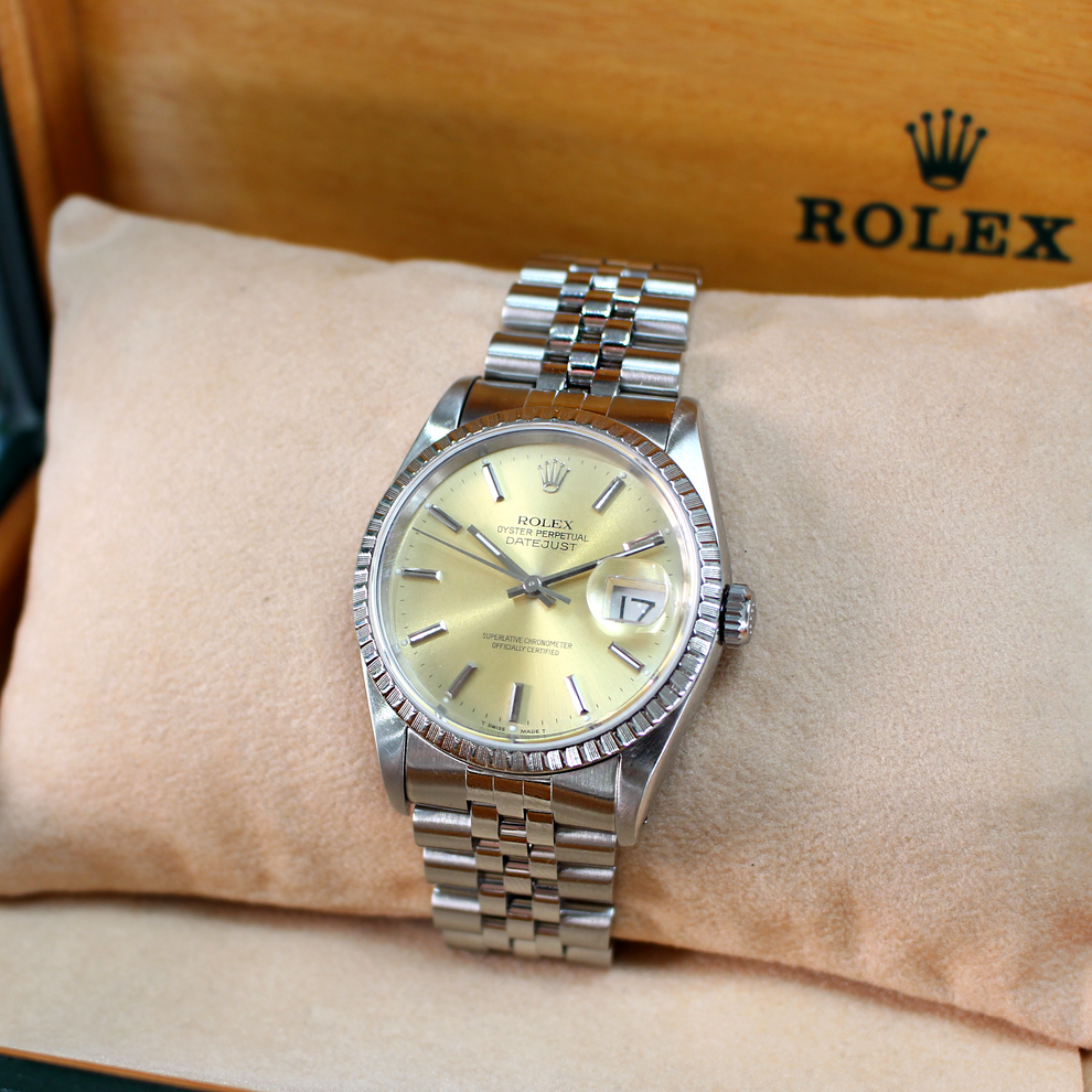 Silver Rolex watch on a wrist with a beige background