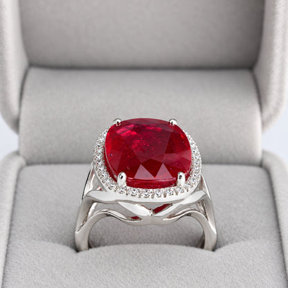 Side view of oval glass-filled ruby and natural diamond halo ring showing open split shoulders in presentation box