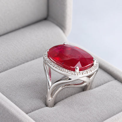 Angled view of glass-filled ruby and natural diamond halo ring in a jewellery presentation box