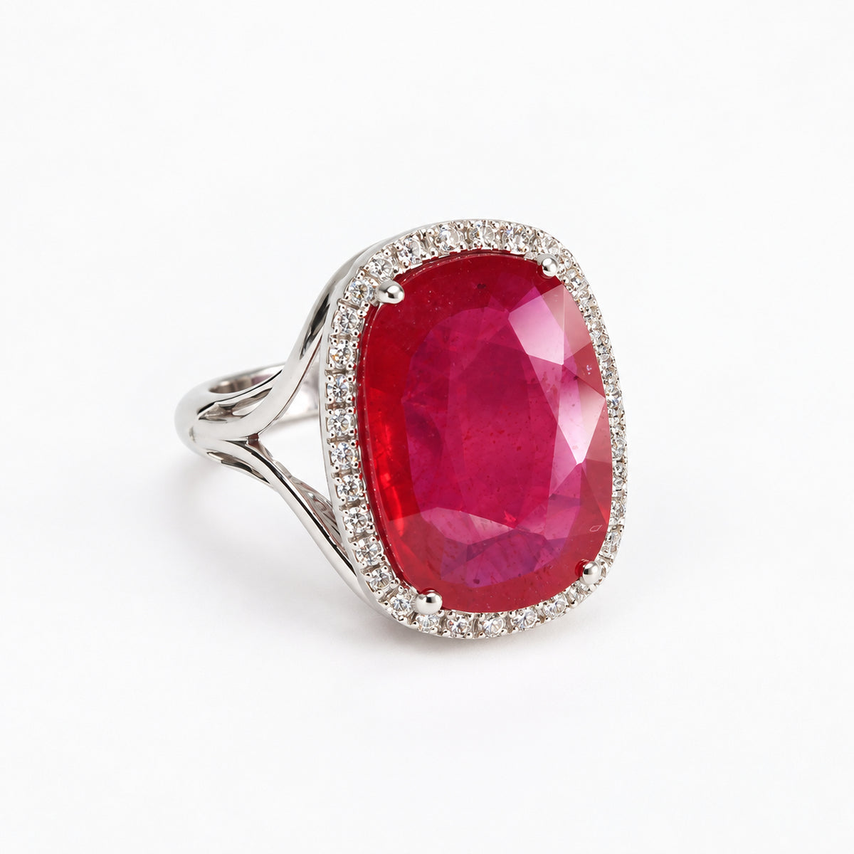 Three-quarter left view of oval red glass-filled ruby ring with natural diamond halo in 18ct white gold