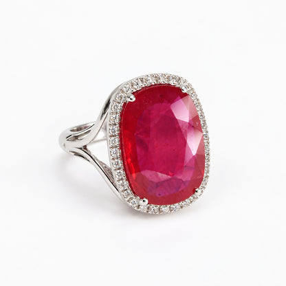 Three-quarter left view of oval red glass-filled ruby ring with natural diamond halo in 18ct white gold