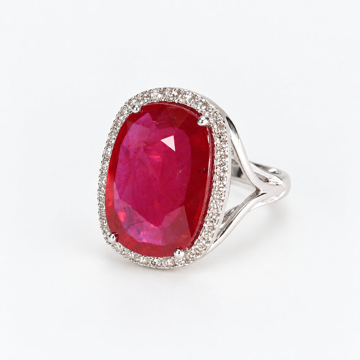 Three-quarter right view of 18ct white gold ruby ring showing oval glass-filled centre and surrounding diamonds
