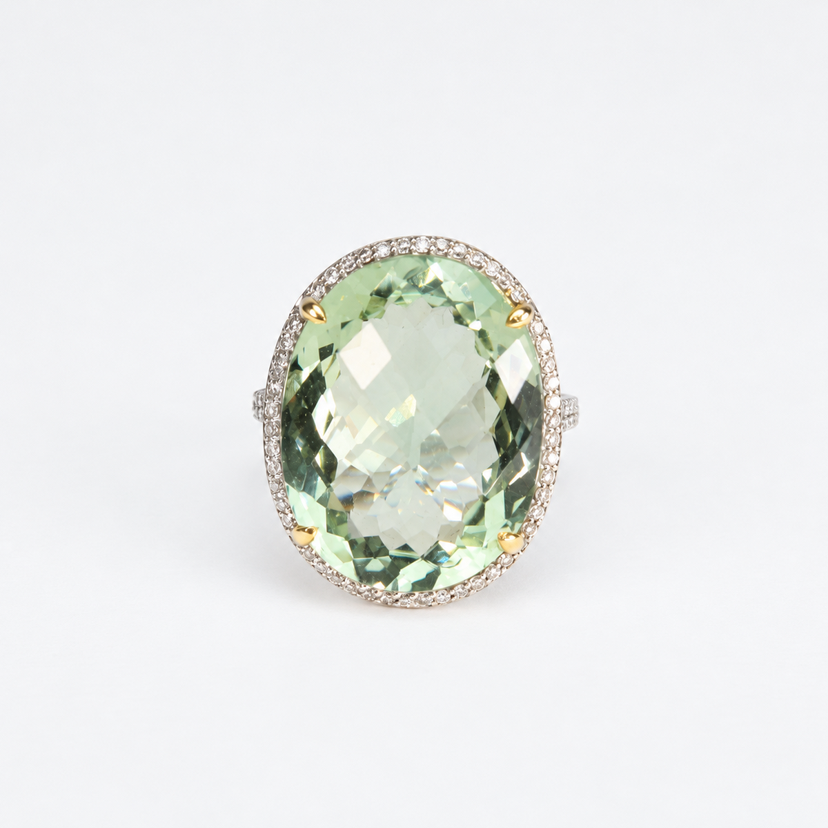 Top view of oval pale green amethyst gemstone framed by a natural diamond halo in an 18ct white gold ring