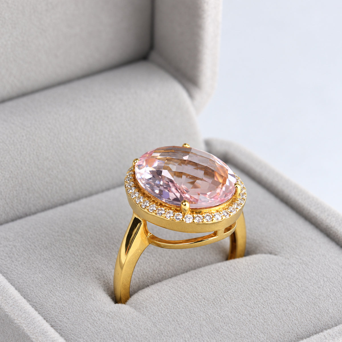 Three-quarter view of oval morganite and diamond halo ring in a grey jewellery box