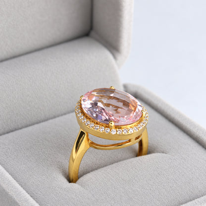 Three-quarter view of oval morganite and diamond halo ring in a grey jewellery box