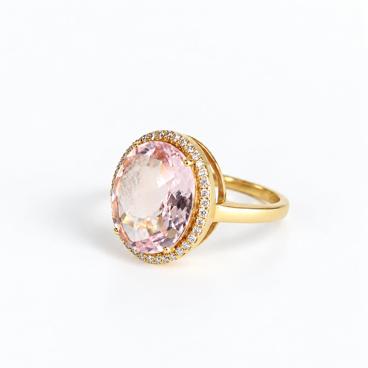 Side angle of oval pink beryl ring showing diamond halo and polished yellow gold band
