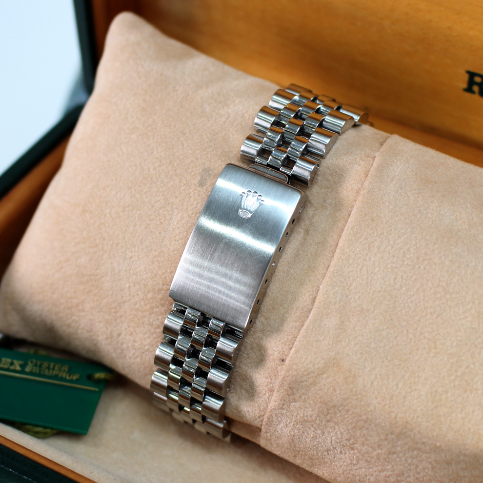 Silver watch band on a beige cushion with a blurred background