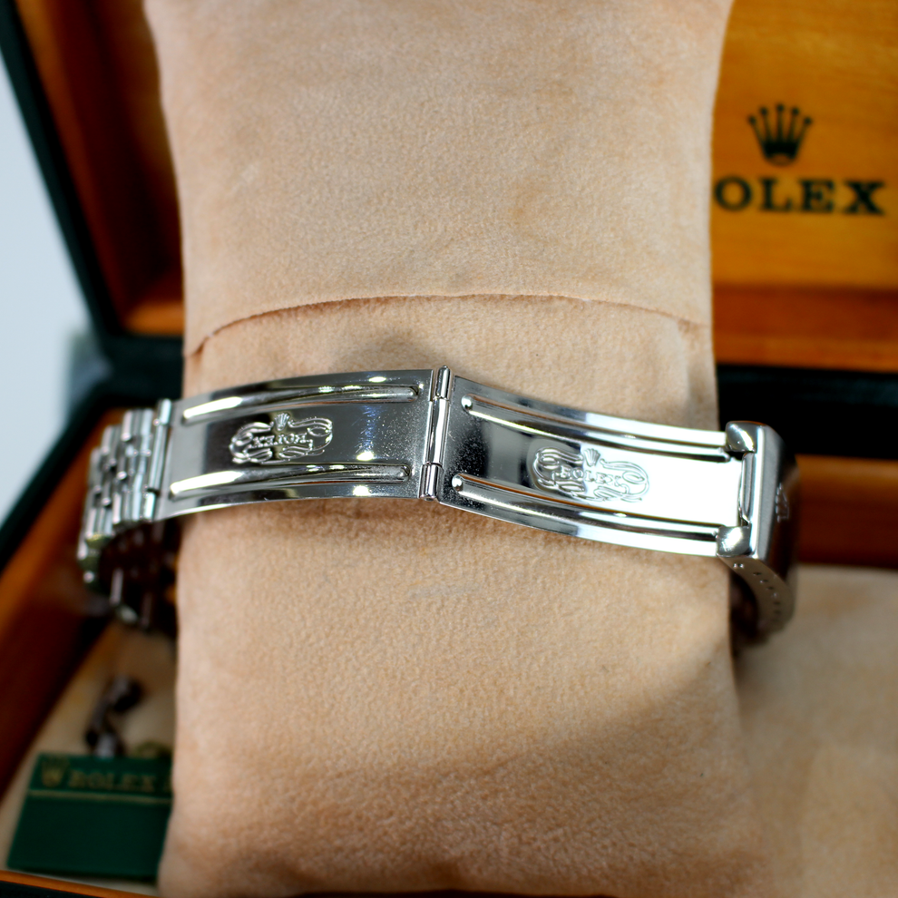 Silver bracelet on a wrist with a Rolex box in the background