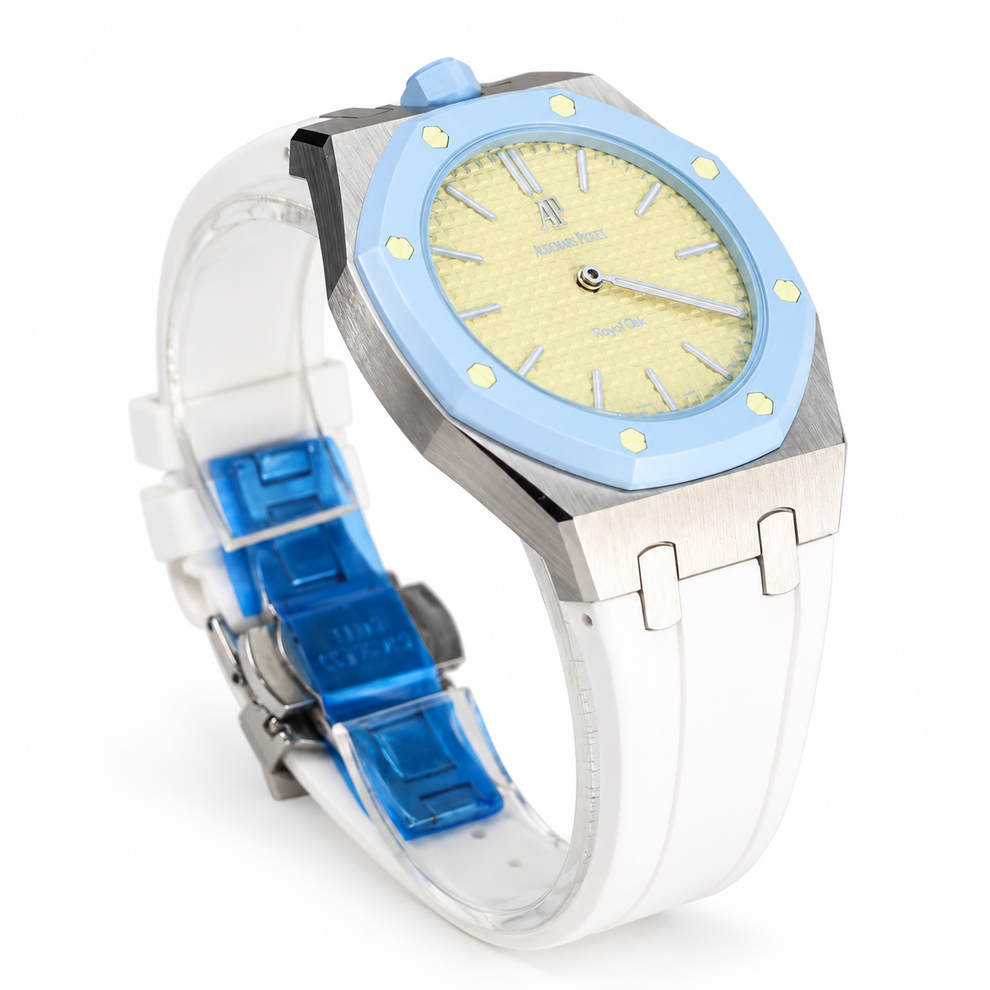 A luxury watch with a light blue bezel, a pale yellow dial, a brushed stainless steel case, and a white rubber strap with a translucent blue buckle.