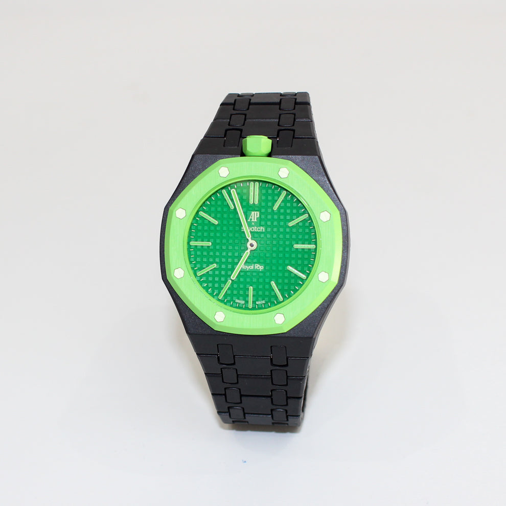 A wristwatch with a black link bracelet, black case, and a vibrant green dial and bezel, photographed on a plain white background.