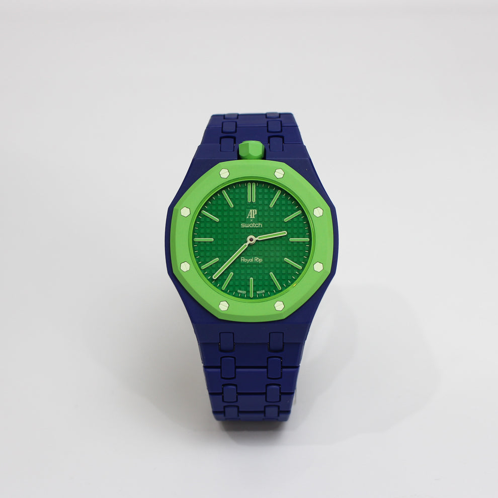A Royal Oak Date watch with a dark blue metal bracelet and a bright green bezel and dial, shown on a light gray background.