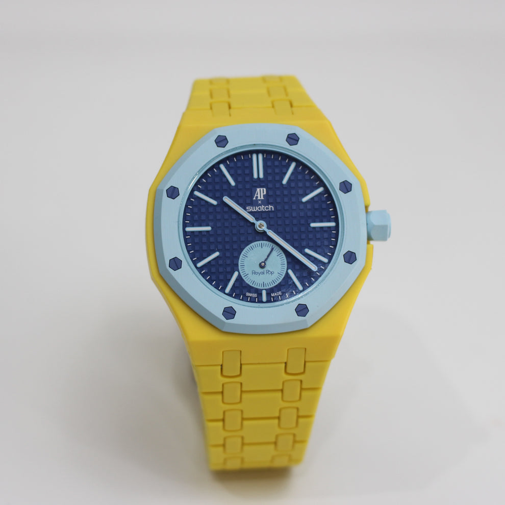 Royal Pop LAN BA front view with yellow linked bracelet and case, dark-blue dial and light-blue bezel