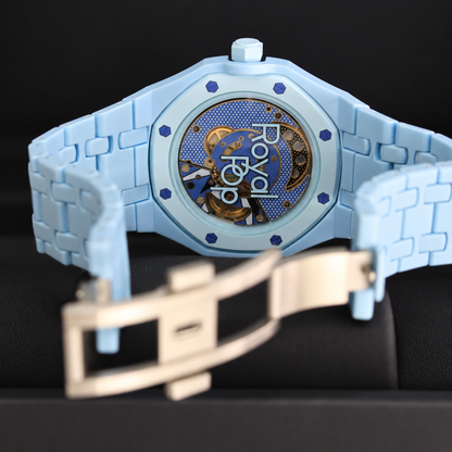 Royal Pop LAN BA transparent caseback showing the movement with light-blue linked bracelet and open folding clasp