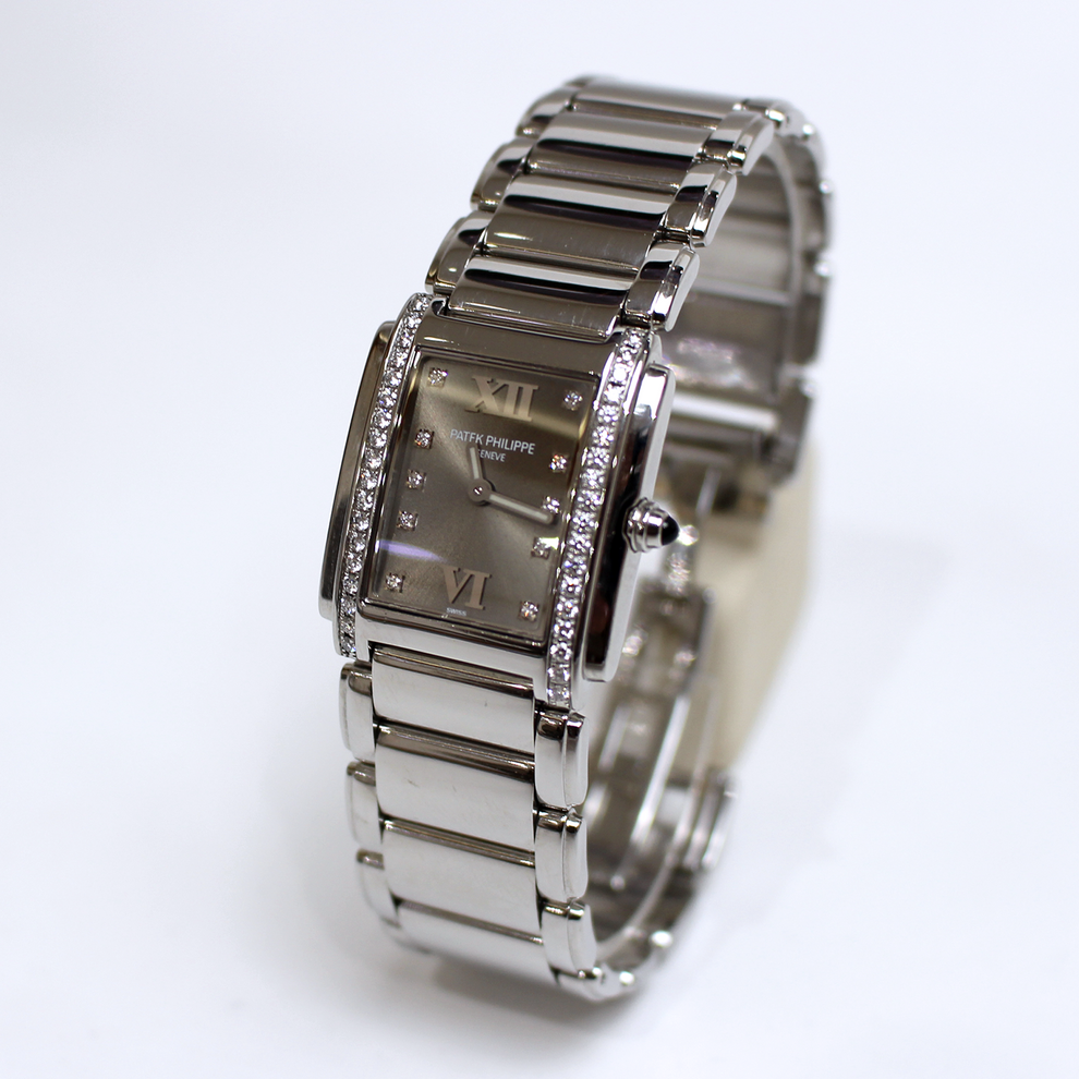 A silver-tone stainless steel women's watch with a rectangular dial, crystal-embellished bezel, and matching metal link bracelet, photographed on a clean white background.