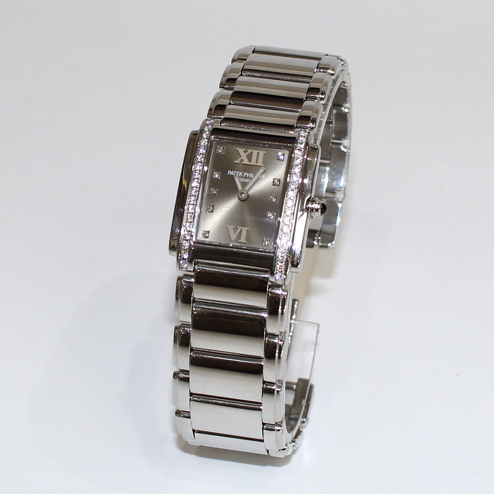 A silver-tone stainless steel women's watch with a rectangular dial, Roman numeral hour markers, crystal-set bezel, and matching metal link bracelet, photographed on a plain white background.