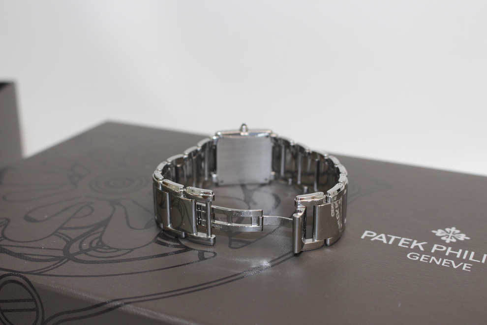A stainless steel Patek Philippe wristwatch bracelet displayed on top of its dark brown Patek Philippe Geneva box, with a white background.