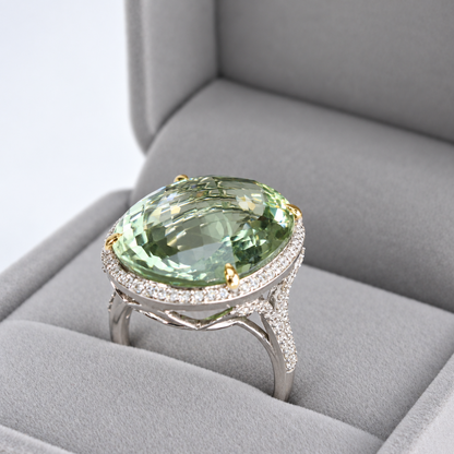 Angled presentation view of oval green amethyst ring with diamond halo and elevated gallery